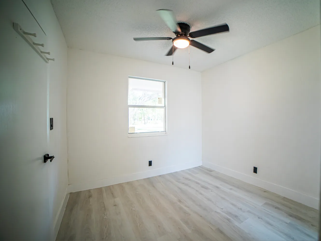 an empty room with a window and a fan