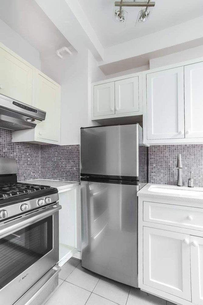 340 West 57th Street, Unit 14E Manhattan, NY 10019 - Photo 10 of 13 a kitchen with granite countertop white cabinets and stainless steel appliances