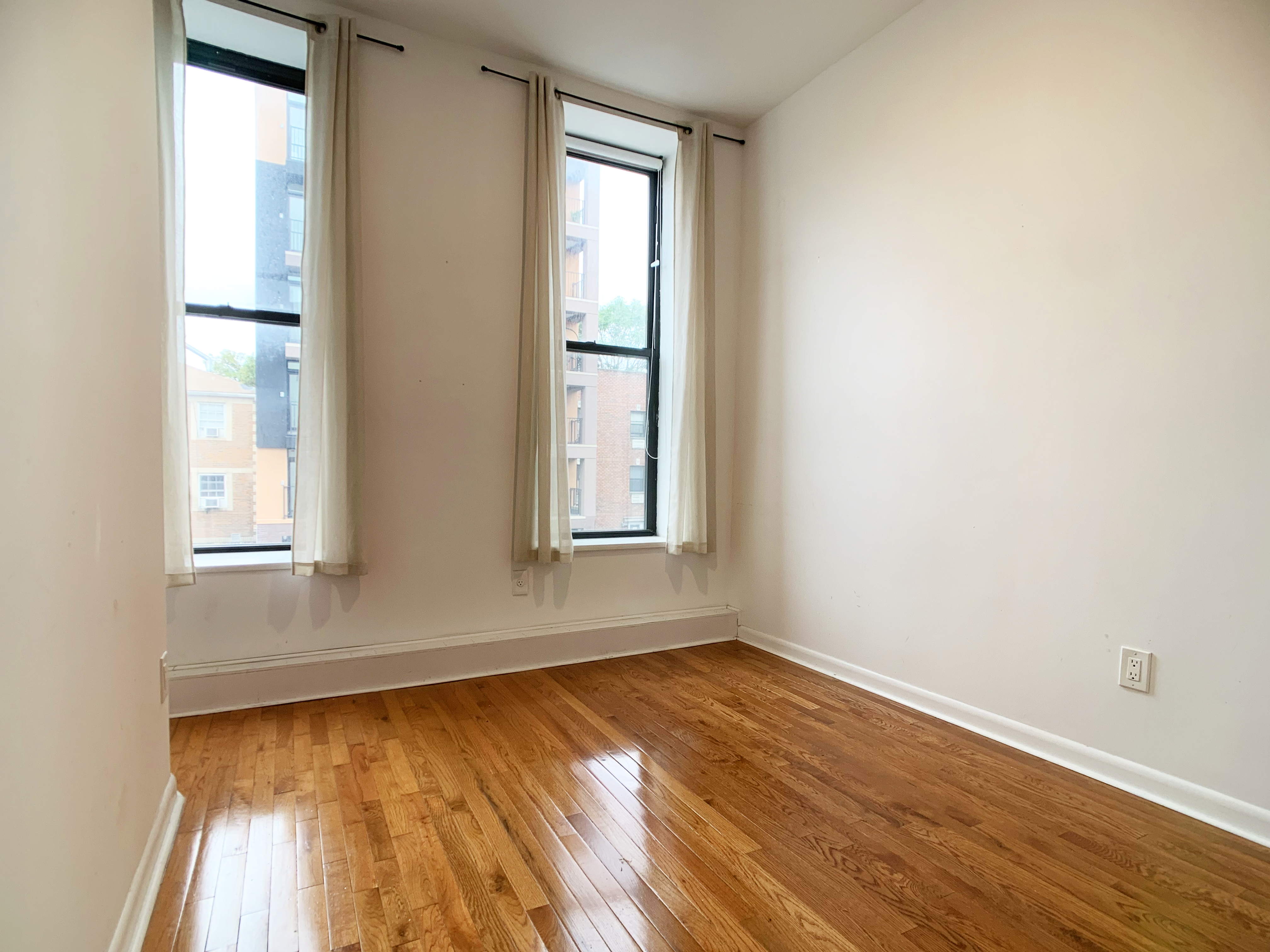 293 Tompkins Avenue, Unit 2 Brooklyn, NY 11221 - Photo 4 of 11 an empty room with wooden floor and windows