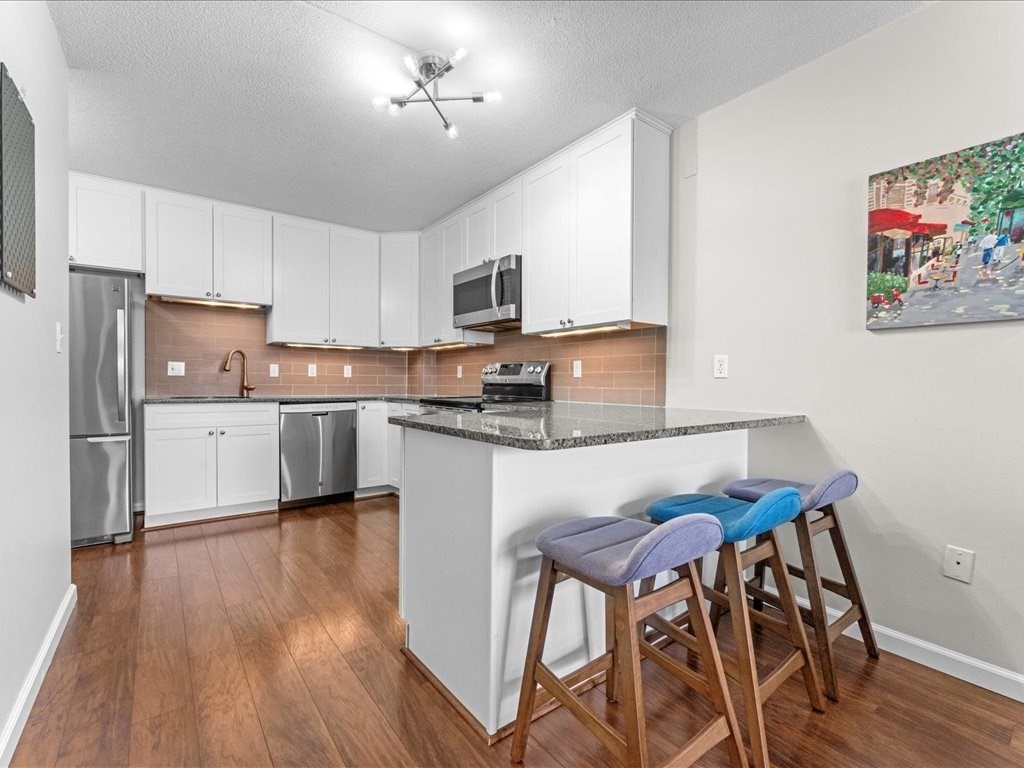 164 Galen Street, Unit 52 Watertown, MA 02472 - Photo 6 of 20 a kitchen with a table chairs refrigerator and microwave
