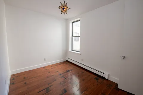 an empty room with a window and a chandelier fan