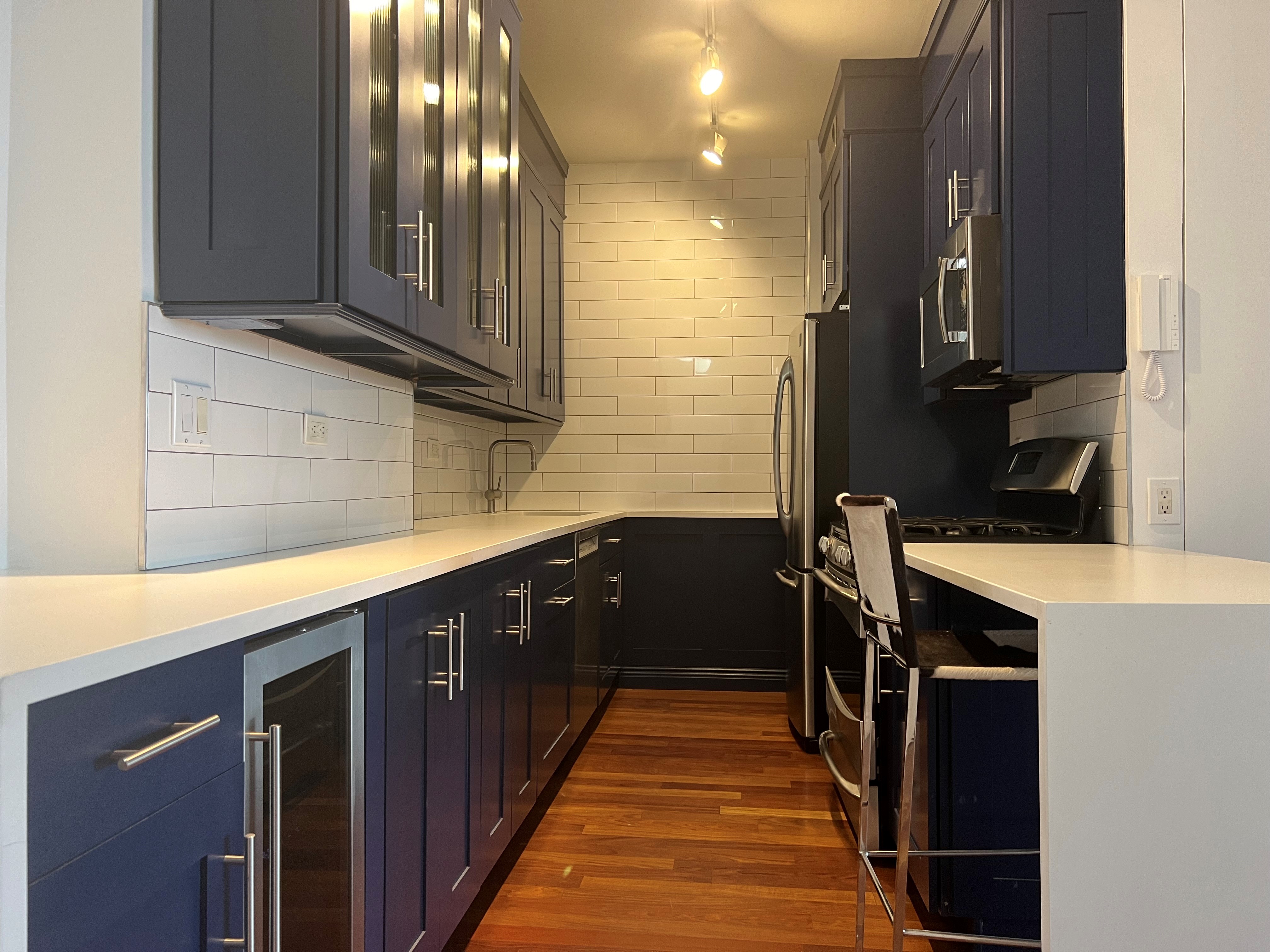 60 East 8th Street, Unit 23D Manhattan, NY 10003 - Photo 9 of 16 a kitchen with wooden cabinets and a sink