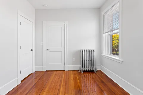 a view of empty room with wooden floor and fan