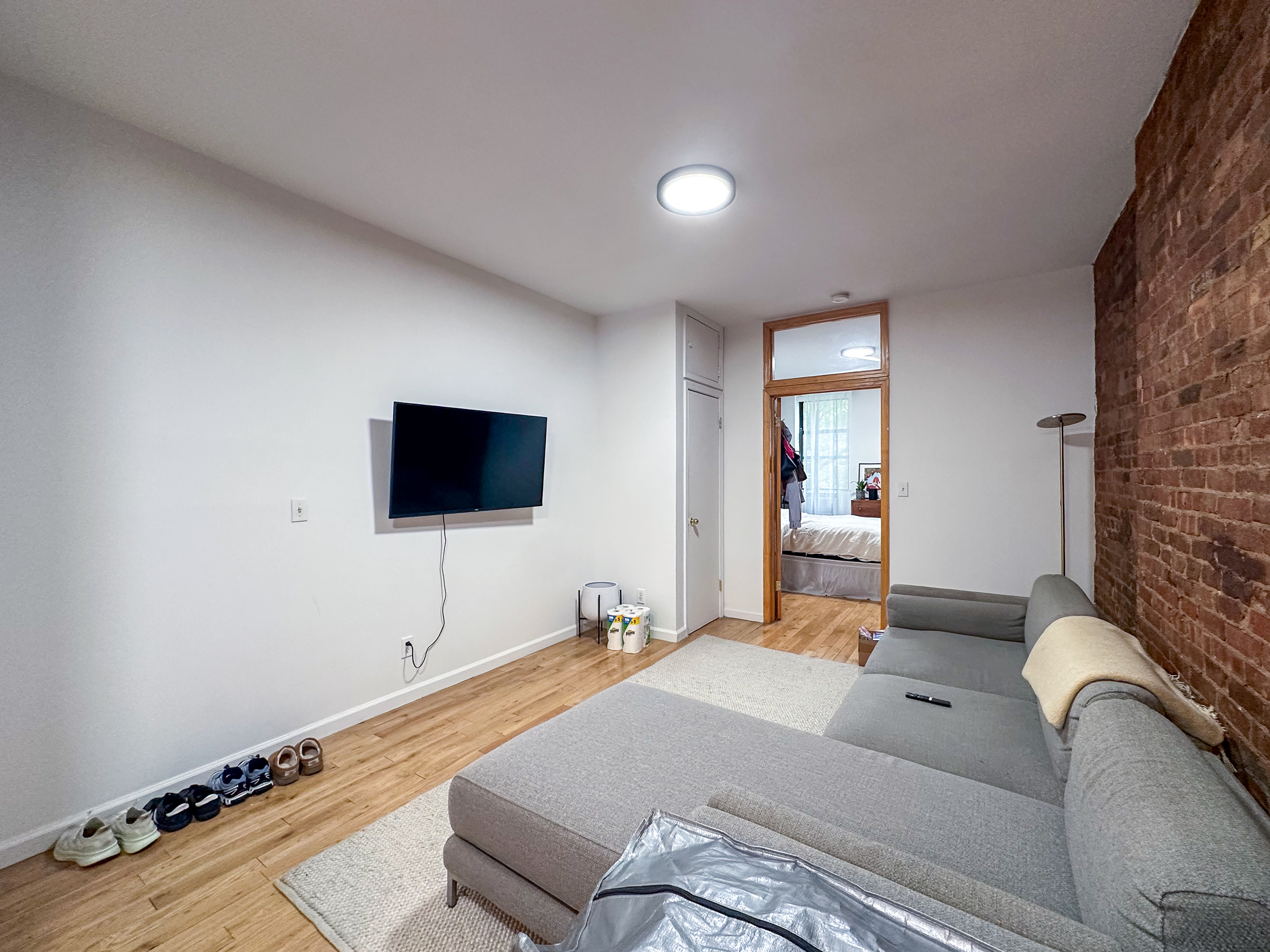 215 East 5th Street, Unit 7 Manhattan, NY 10003 - Photo 4 of 15 a living room with a bed furniture and a flat screen tv