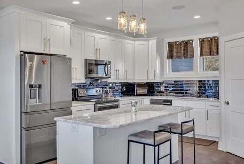 a kitchen with stainless steel appliances granite countertop a refrigerator a stove a sink a dining table and chairs with wooden floor