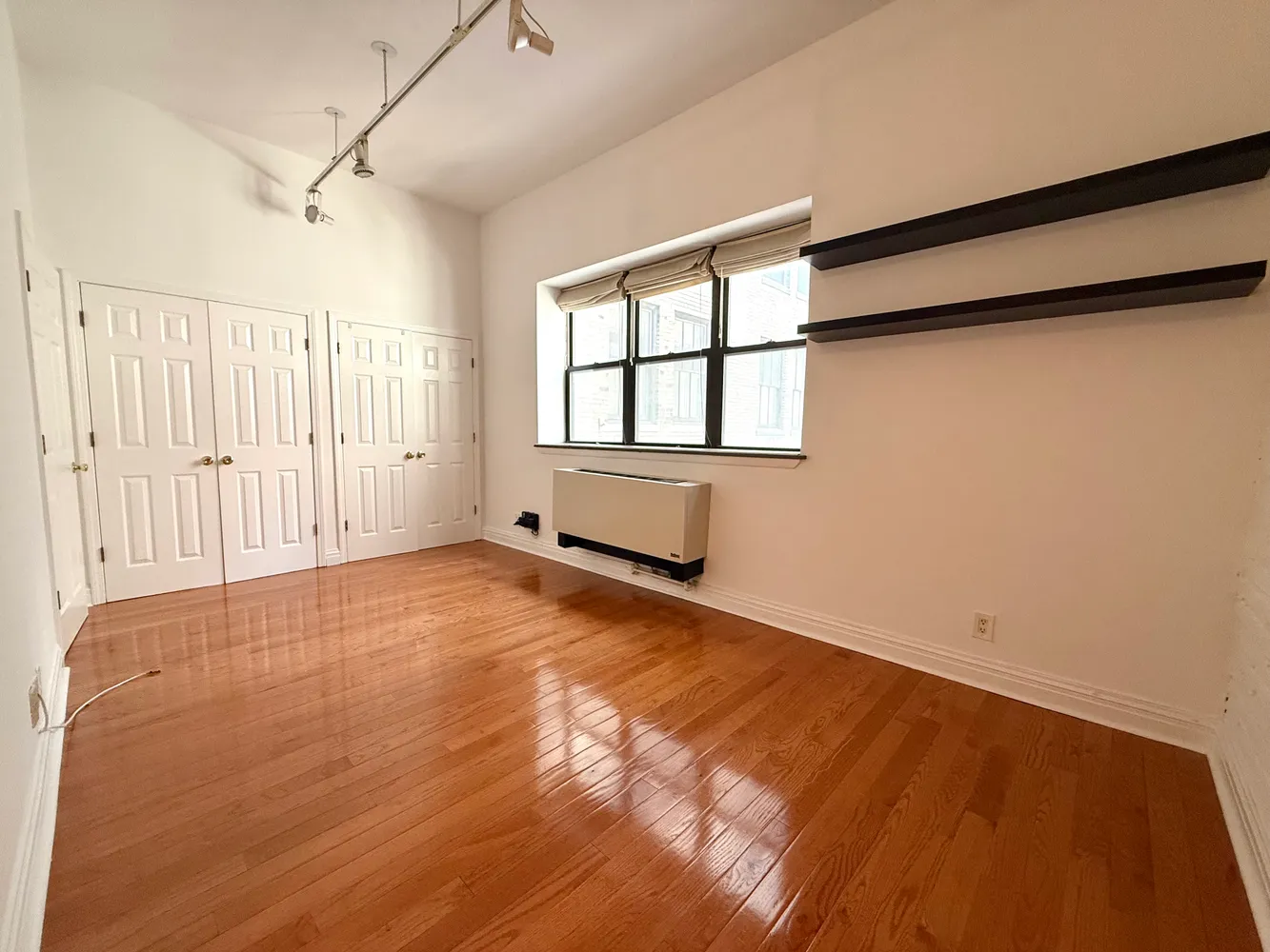 an empty room with wooden floor and windows