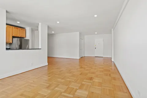 a view of a hallway with wooden floor and cabinets
