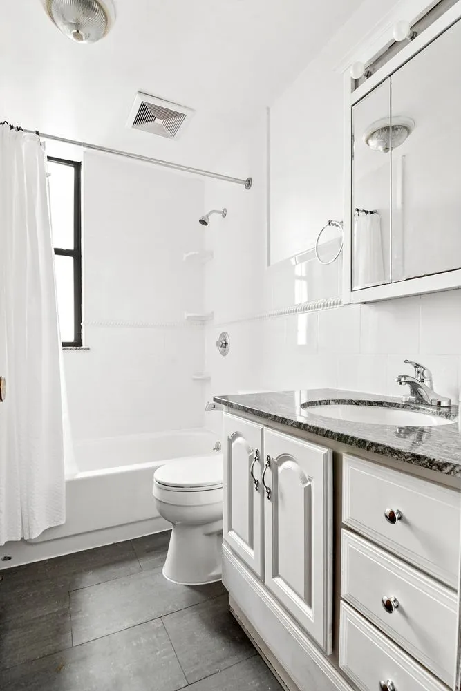 a bathroom with a granite countertop sink a toilet and a shower