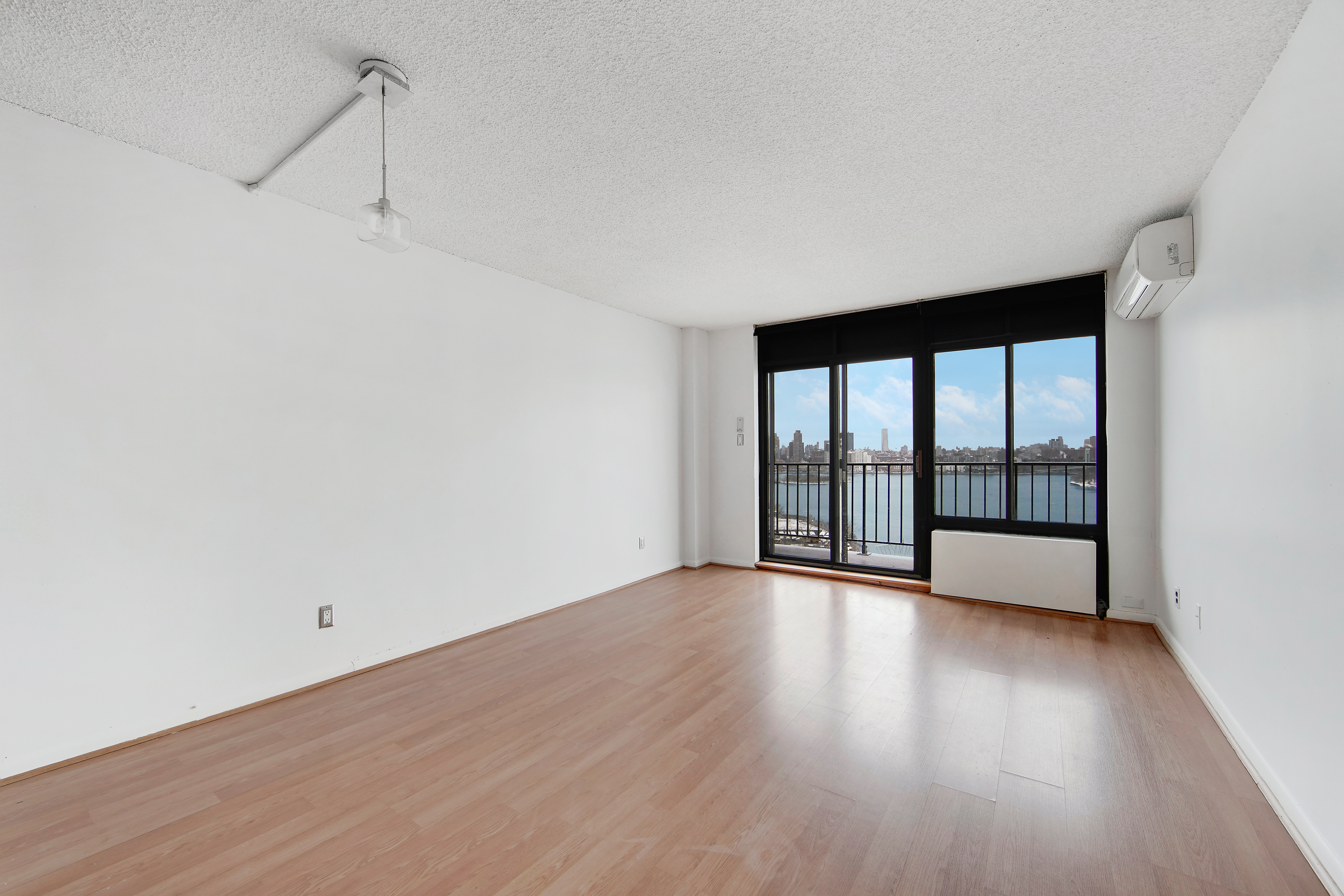 25-40 Shore Boulevard, Unit 15S Queens, NY 11102 - Photo 8 of 21 a view of an empty room with wooden floor and a window