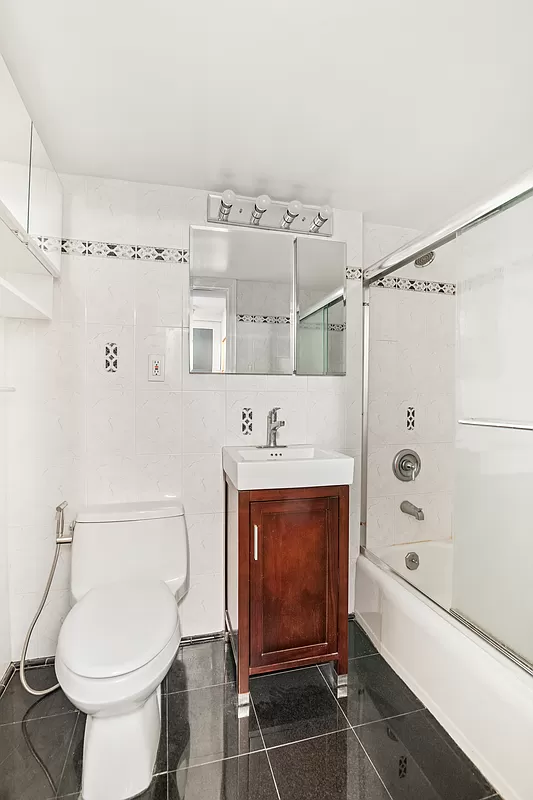 153 East 57th Street, Unit 17F Manhattan, NY 10022 - Photo 5 of 8 a bathroom with a sink a toilet and shower