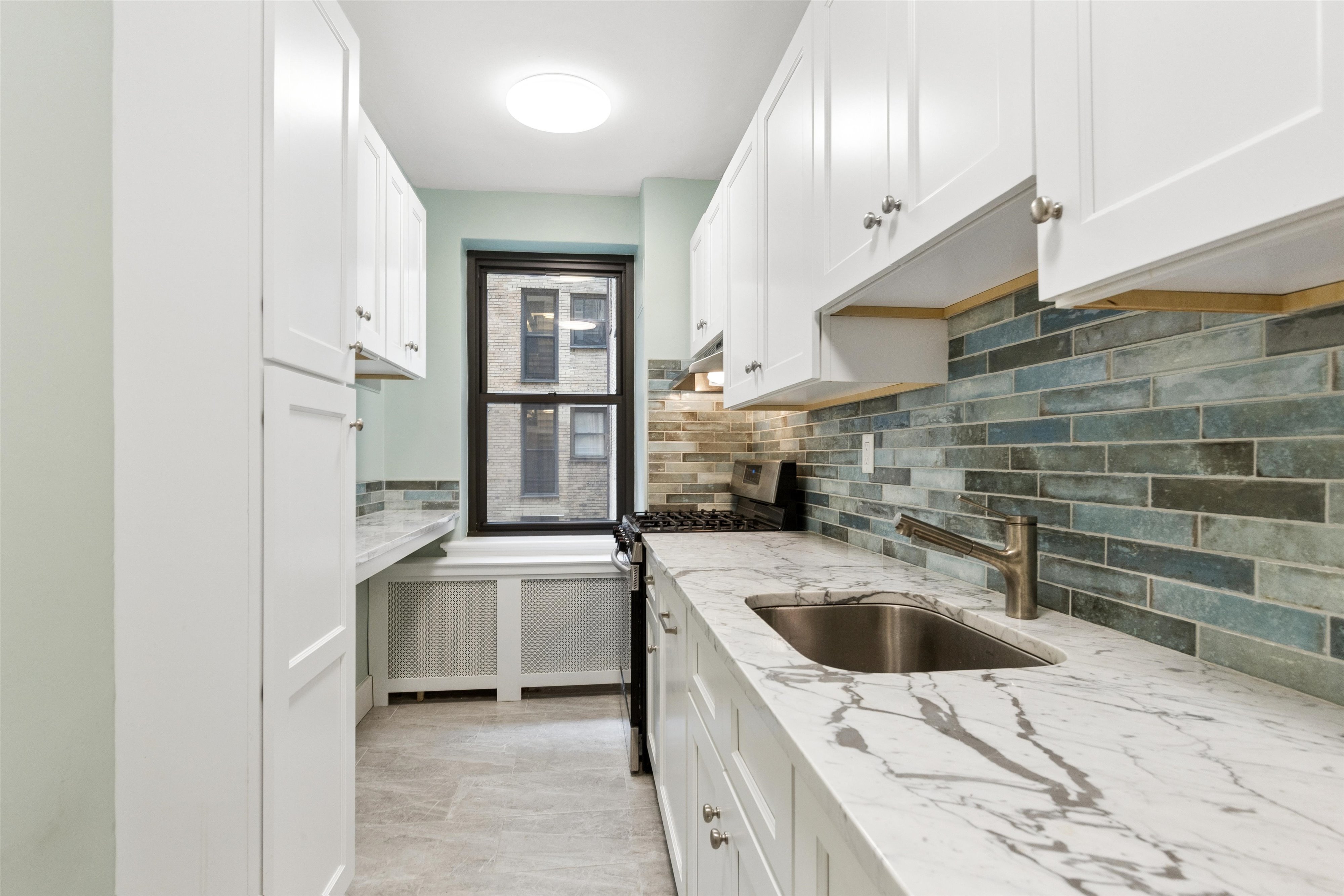 444 East 52nd Street, Unit 3C Manhattan, NY 10022 - Photo 6 of 19 a kitchen with kitchen island a sink a stove and refrigerator
