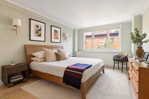 a bedroom with a bed table chair and painting on the wall