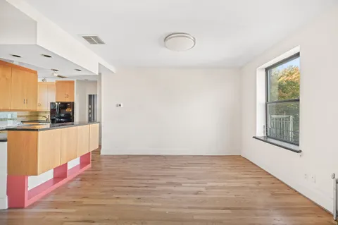 a view of an empty room with window and wooden floor