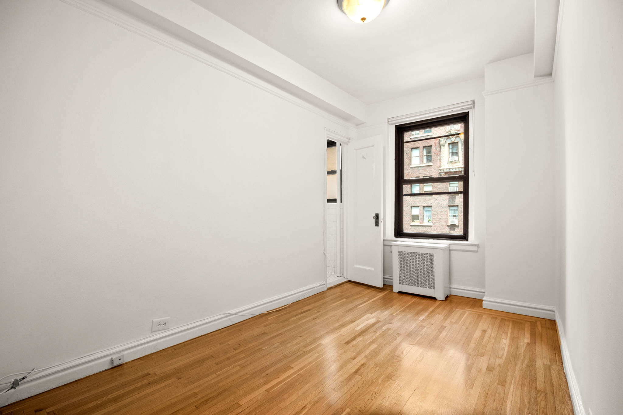 235 West End Avenue, Unit 12H Manhattan, NY 10023 - Photo 9 of 16 an empty room with wooden floor and windows