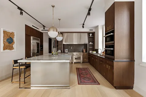 a kitchen with kitchen island a counter top space a sink stainless steel appliances and cabinets