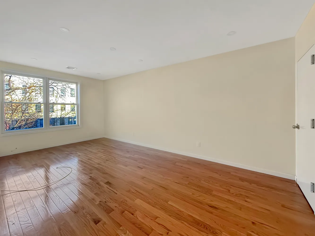 an empty room with wooden floor and windows