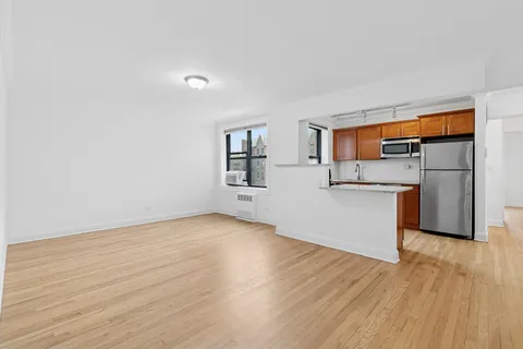 a view of a kitchen with wooden floor and a hallway