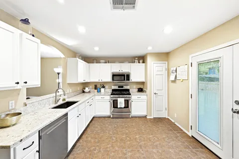 a large kitchen with granite countertop a sink and stainless steel appliances