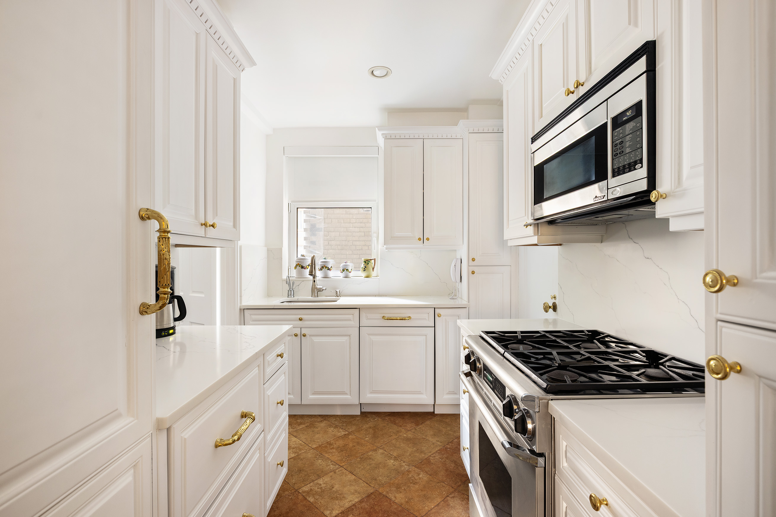 875 5th Avenue, Unit 8D Manhattan, NY 10065 - Photo 5 of 13 a kitchen with stainless steel appliances a sink dishwasher a stove and a microwave oven with cabinets