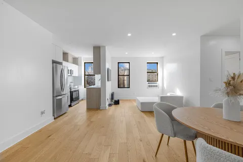 a kitchen with stainless steel appliances a dining table chairs and refrigerator