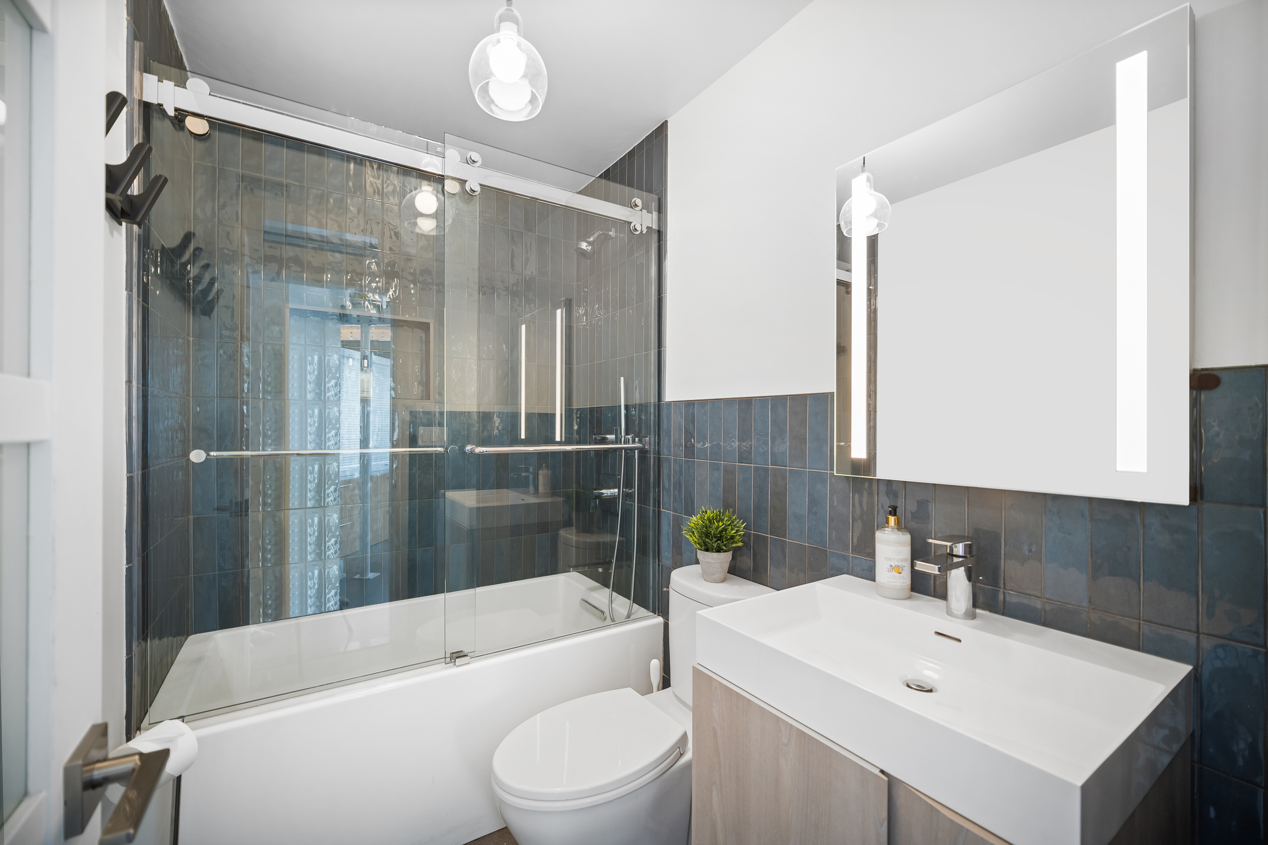 111 4th Avenue, Unit 1J Manhattan, NY 10003 - Photo 9 of 11 a bathroom with a sink a toilet a mirror and shower