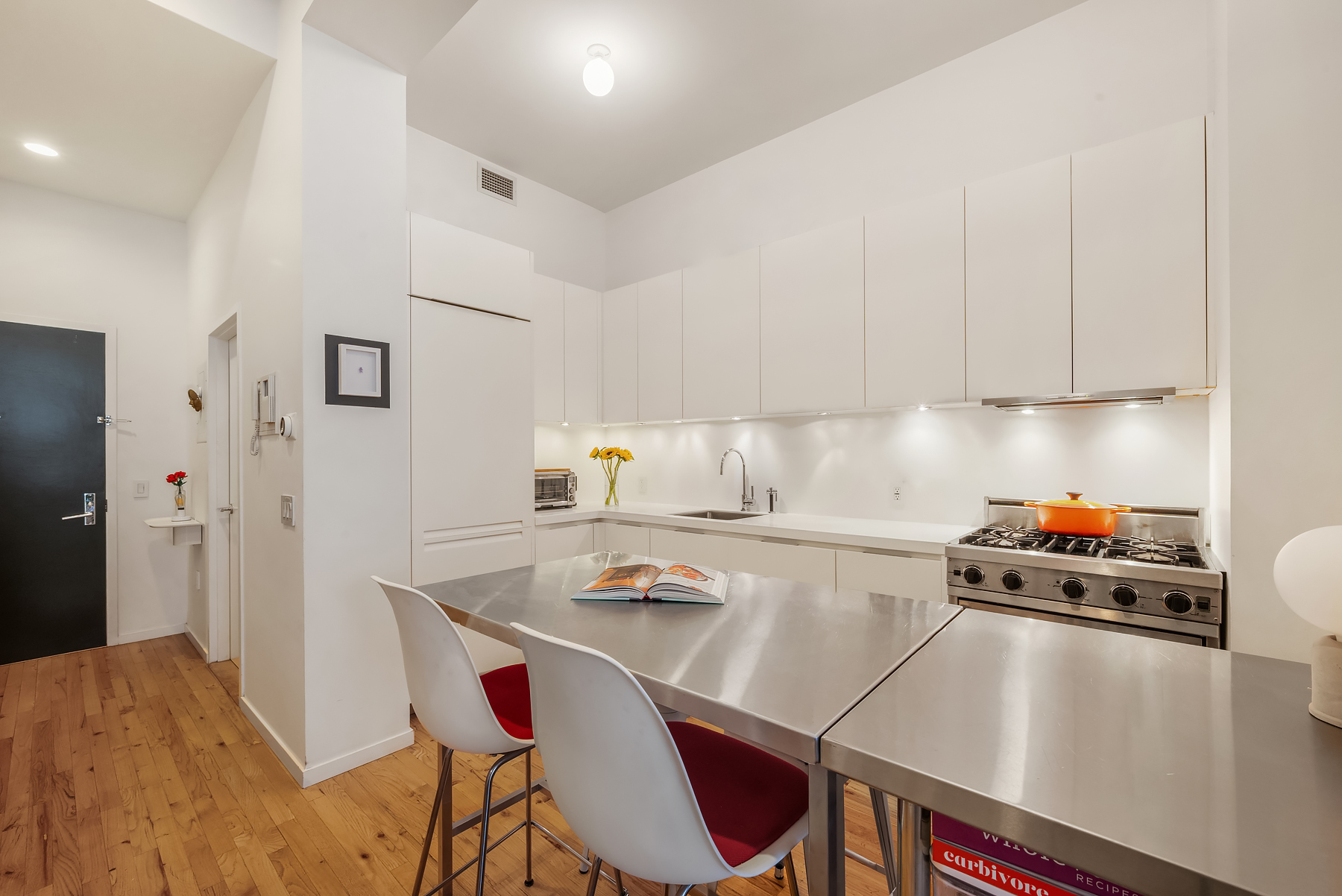 175 East Broadway, Unit 4C Manhattan, NY 10002 - Photo 4 of 14 a kitchen with a dining table cabinets and appliances
