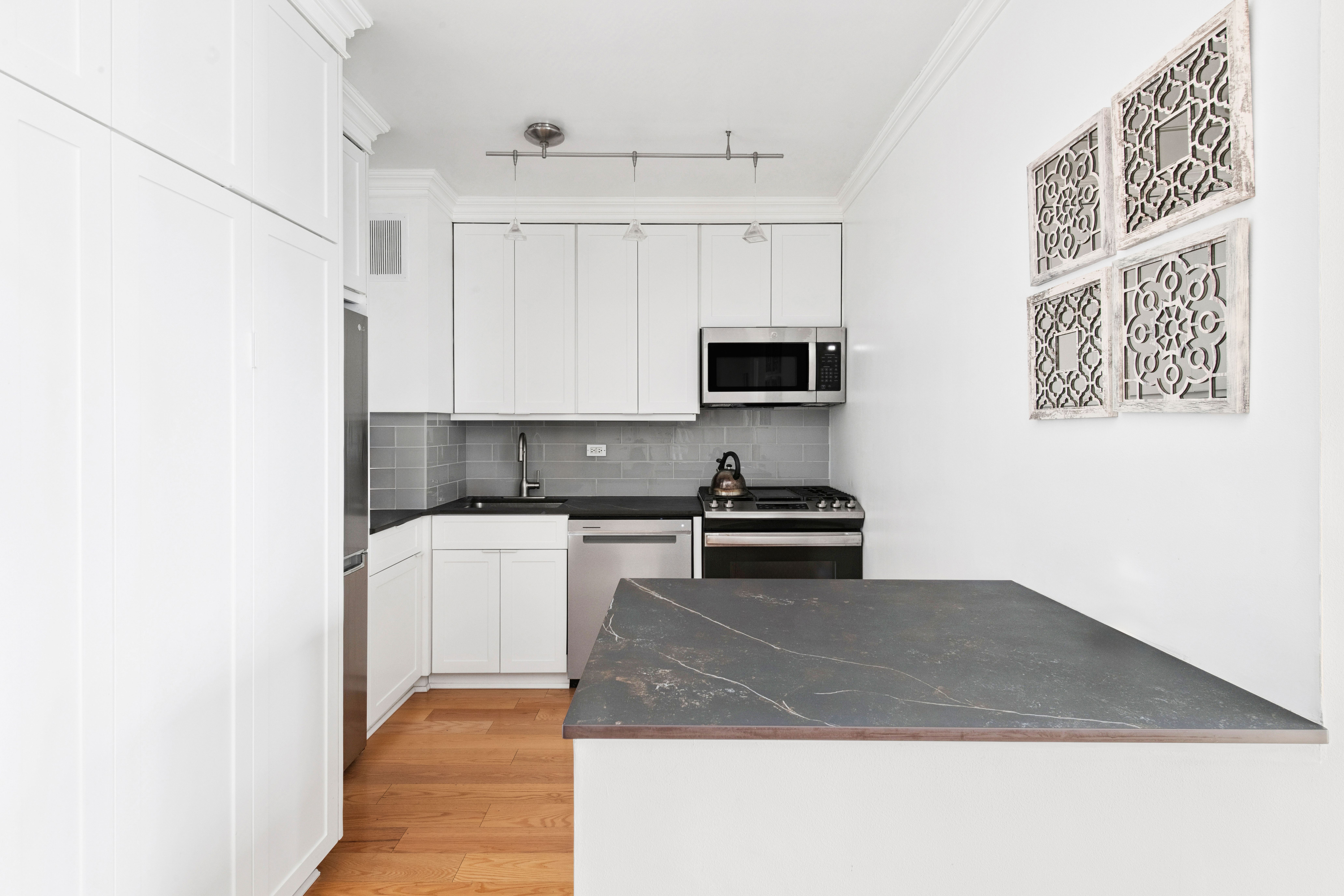 400 East 56th Street, Unit 19O Manhattan, NY 10022 - Photo 5 of 20 a kitchen with stainless steel appliances granite countertop a stove a sink and a microwave