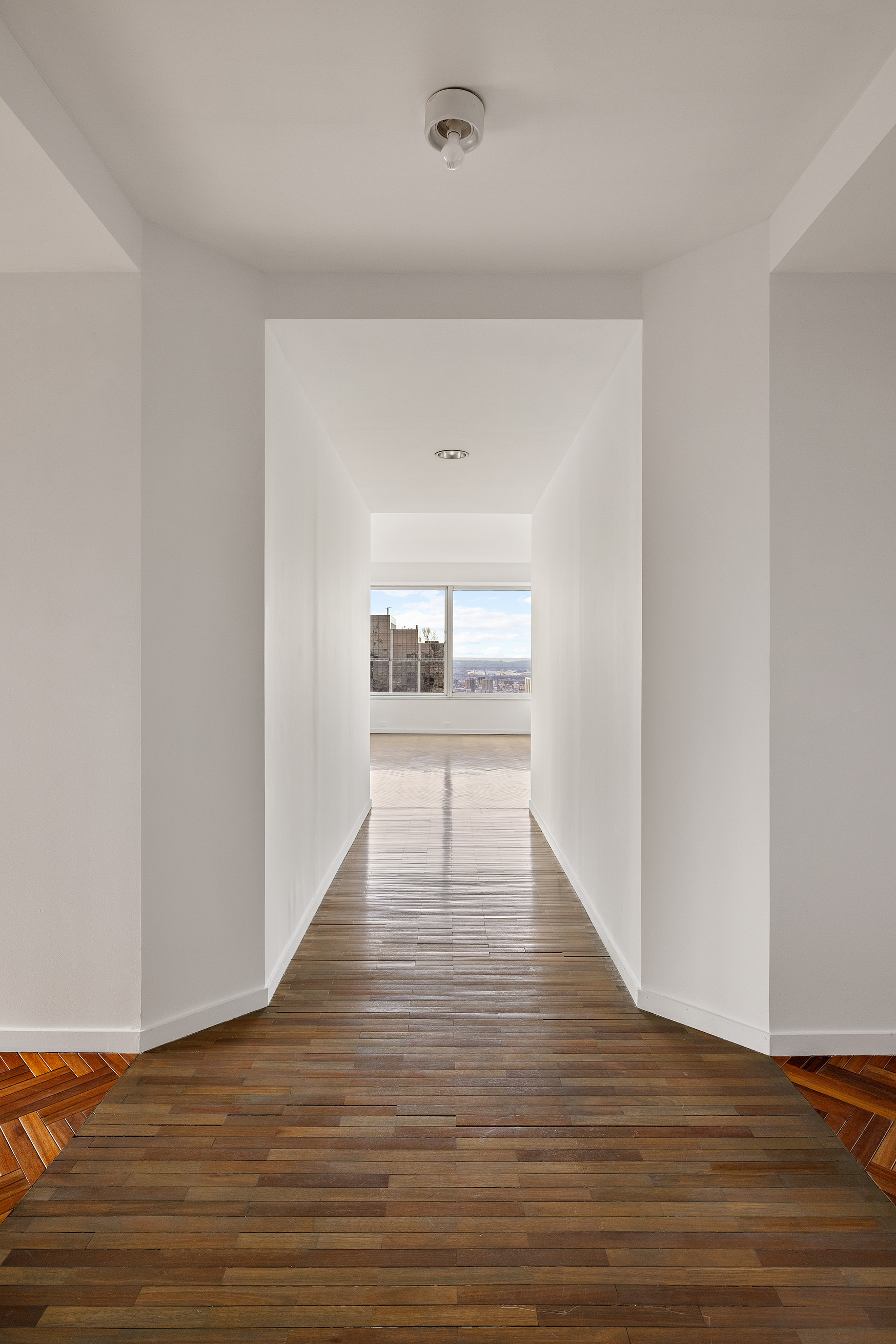 150 West 56th Street, Unit 6204 Manhattan, NY 10019 - Photo 14 of 15 a view of an empty room with wooden floor and a window
