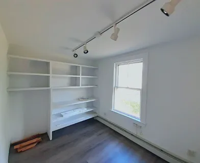 a view of an empty room with a window and wooden floor