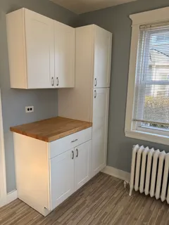a kitchen with a white cabinets and wooden floor