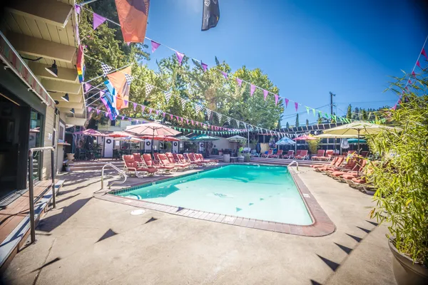 a bedroom with a large bed a flat tv screen on dresser and a chandelier