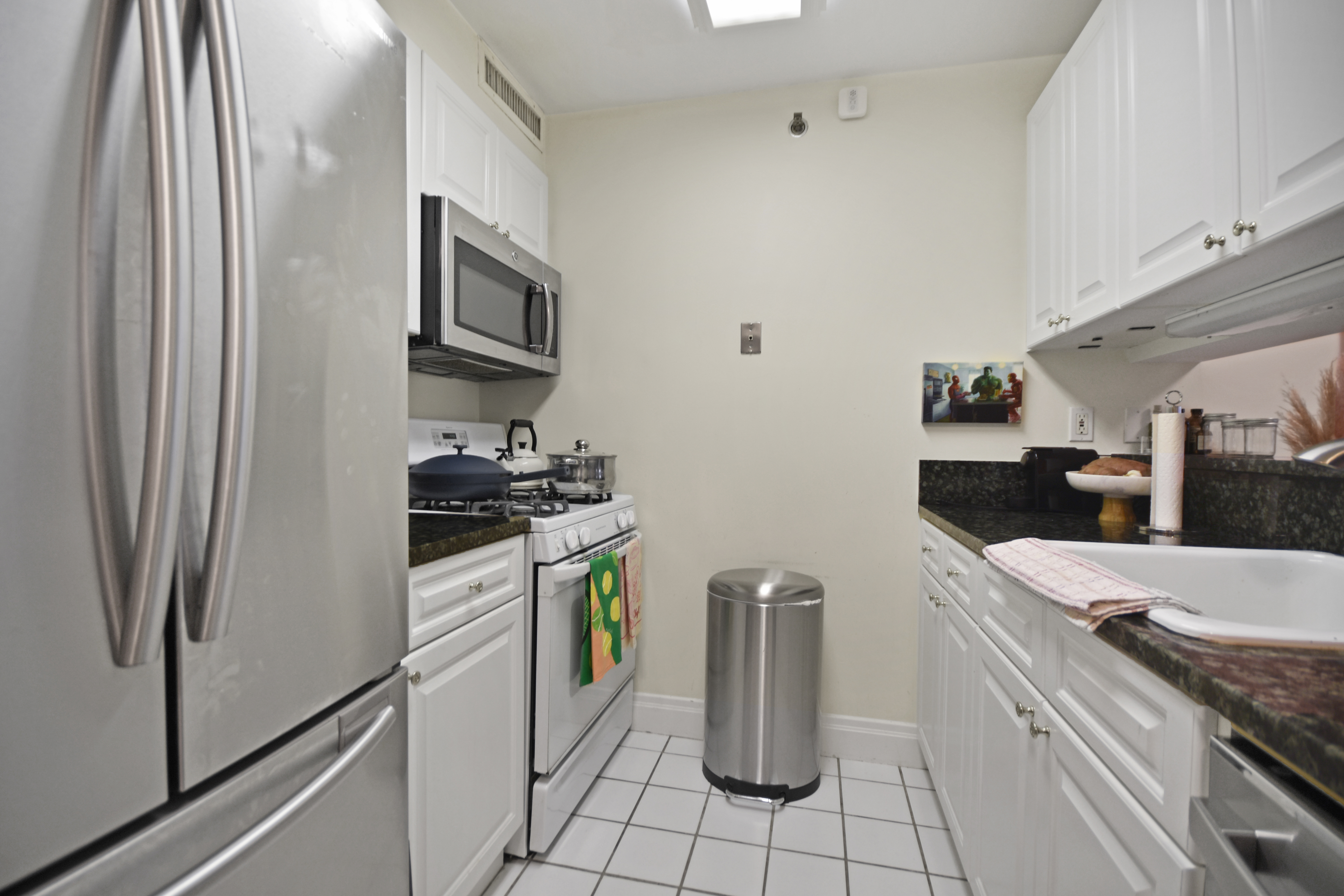 404 East 76th Street, Unit 4A Manhattan, NY 10021 - Photo 4 of 6 a kitchen with granite countertop a sink appliances and cabinets