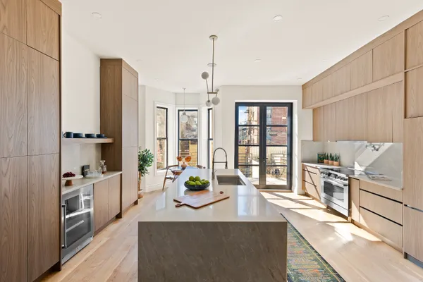 a view of a kitchen with kitchen island a large window cabinets a sink and stainless steel appliances