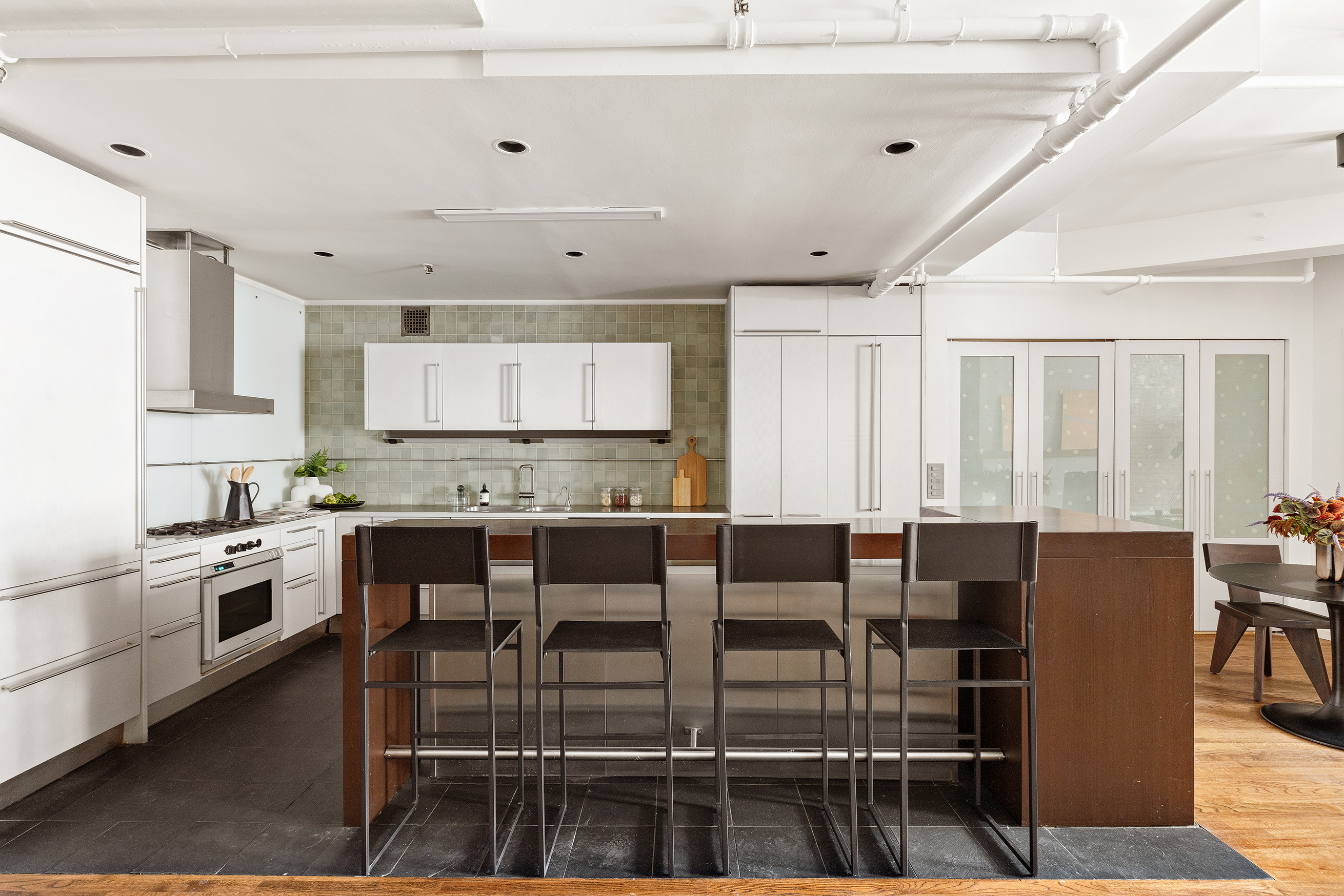 214 West 17th Street, Unit 4B Manhattan, NY 10011 - Photo 4 of 10 a kitchen with stainless steel appliances kitchen island granite countertop a dining table chairs and granite counter tops