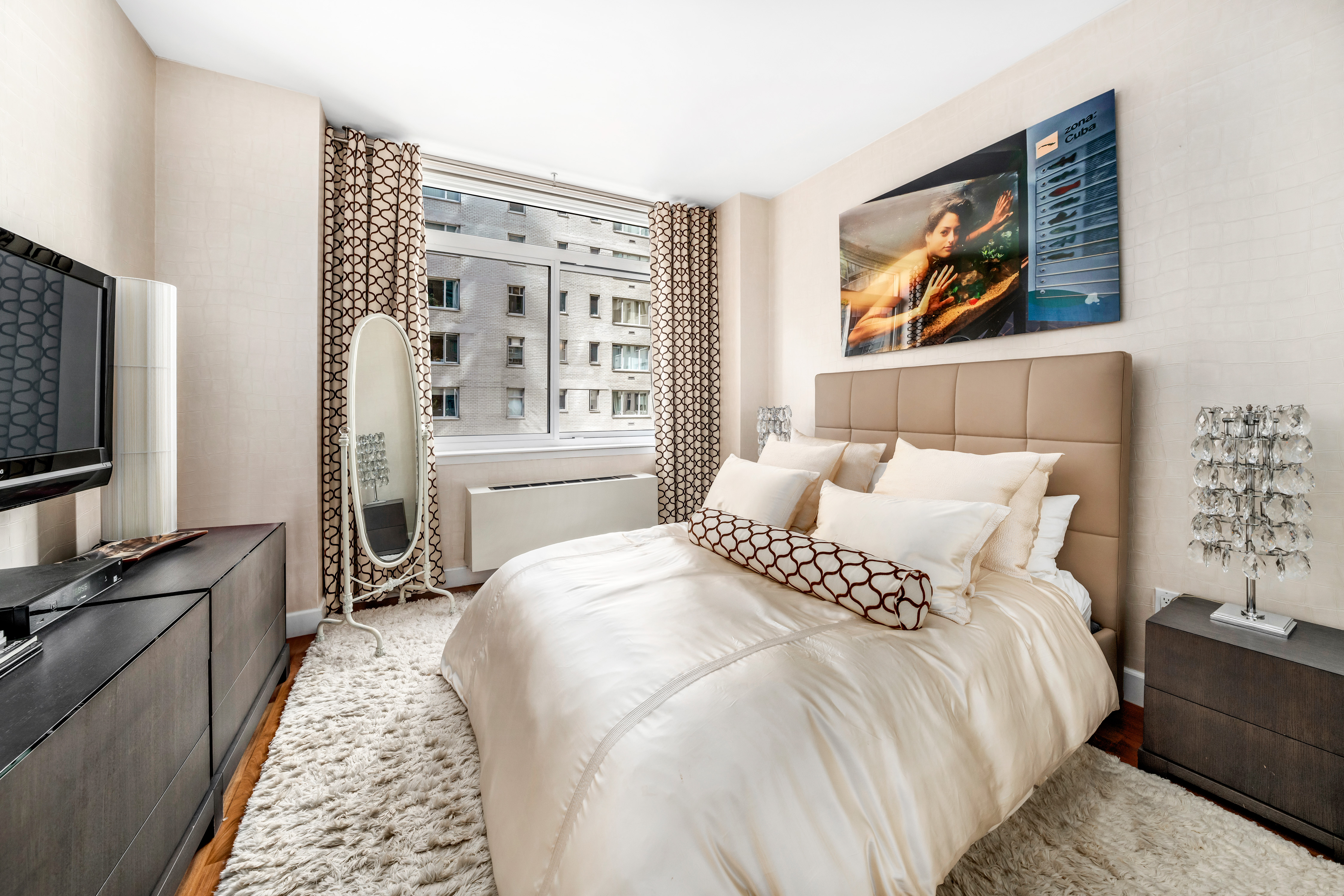 212 East 57th Street, Unit 5C Manhattan, NY 10022 - Photo 6 of 10 a bedroom with a bed a painting on the wall and a flat screen tv