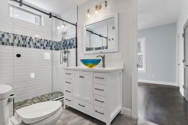 a bathroom with a toilet sink vanity shower and mirror