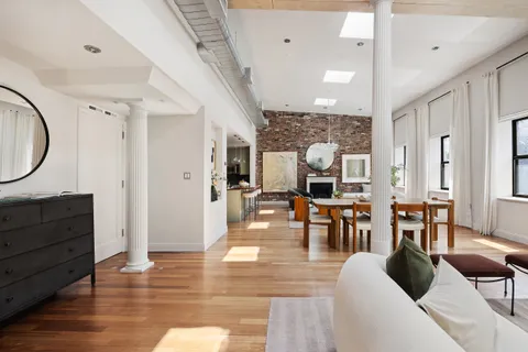 a living room with couches chairs and kitchen view with wooden floor