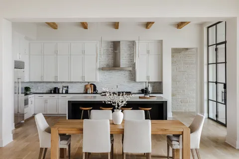 a kitchen with a dining table chairs and cabinets