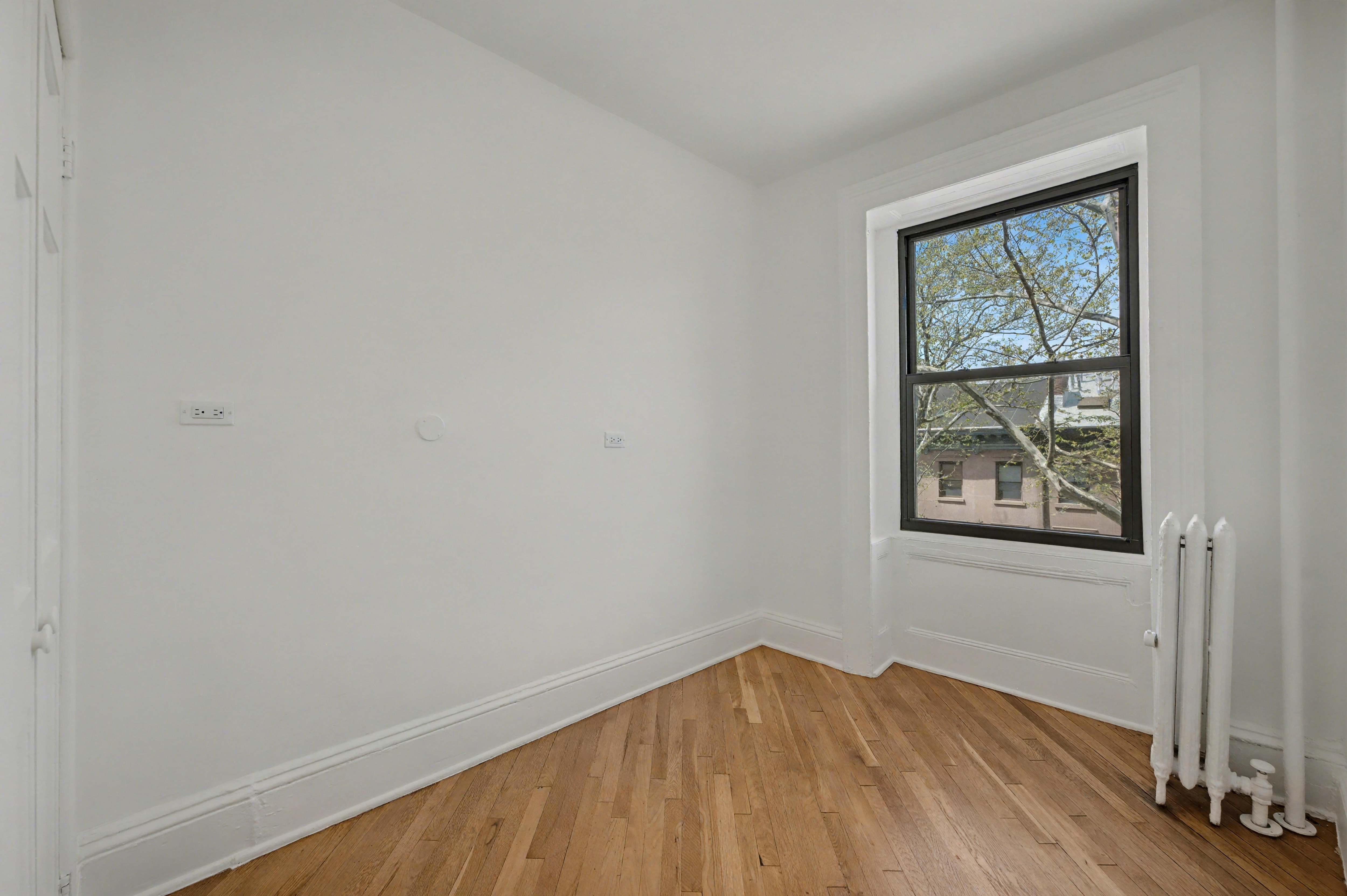 261 Clinton Street, Unit 3 Brooklyn, NY 11201 - Photo 6 of 12 a view of an empty room with wooden floor and a window
