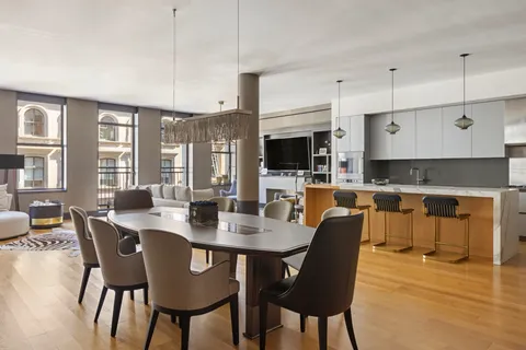 a dining room with stainless steel appliances kitchen island granite countertop a dining table chairs and a refrigerator