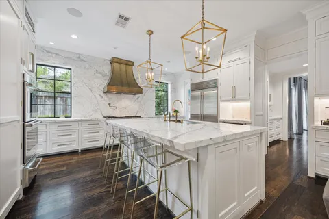 a kitchen with stainless steel appliances granite countertop a kitchen island hardwood floor and a sink