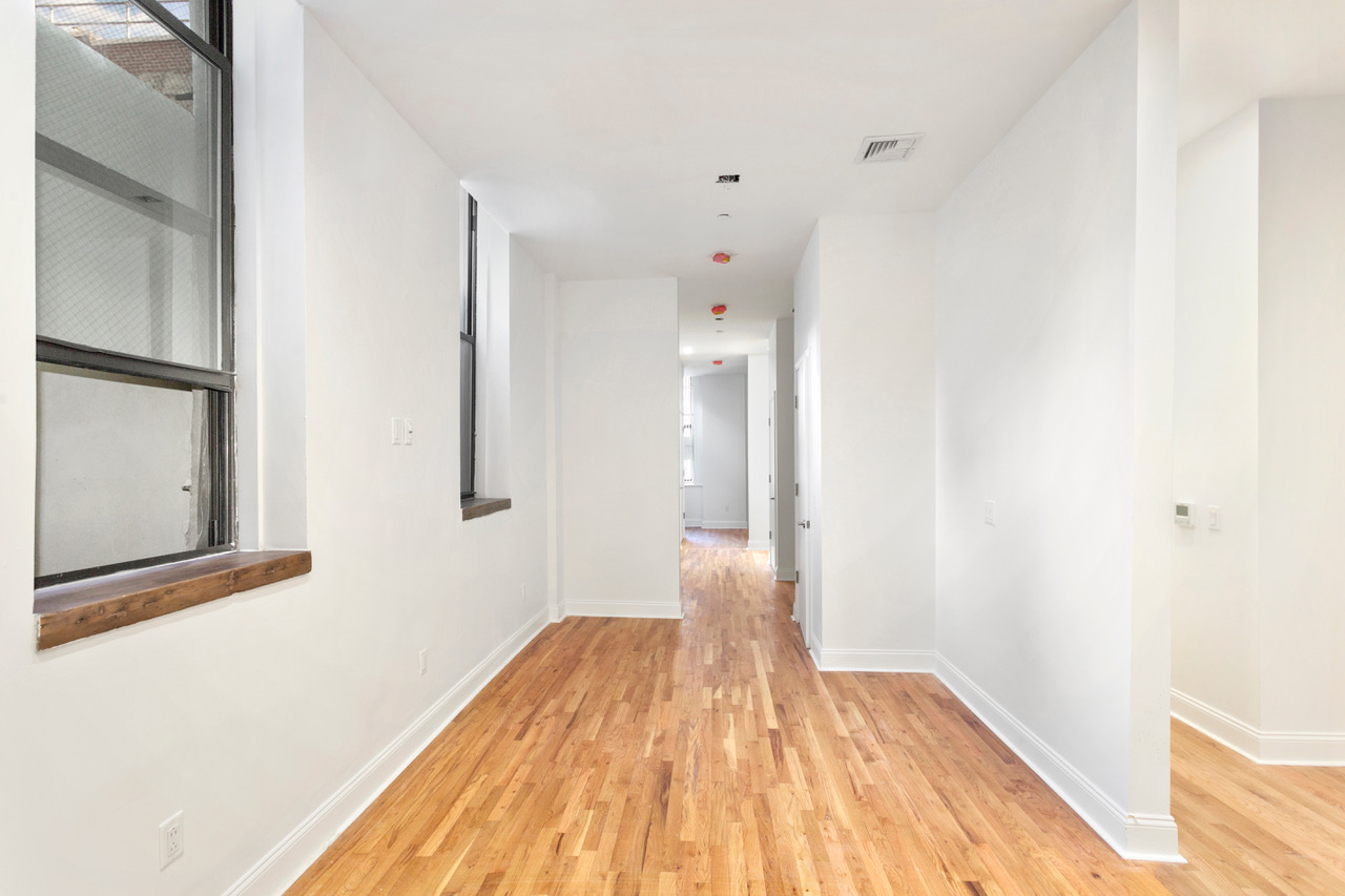 281 Grand Street, Unit 2R Manhattan, NY 10002 - Photo 10 of 11 a view of a bedroom with wooden floor and a bathroom