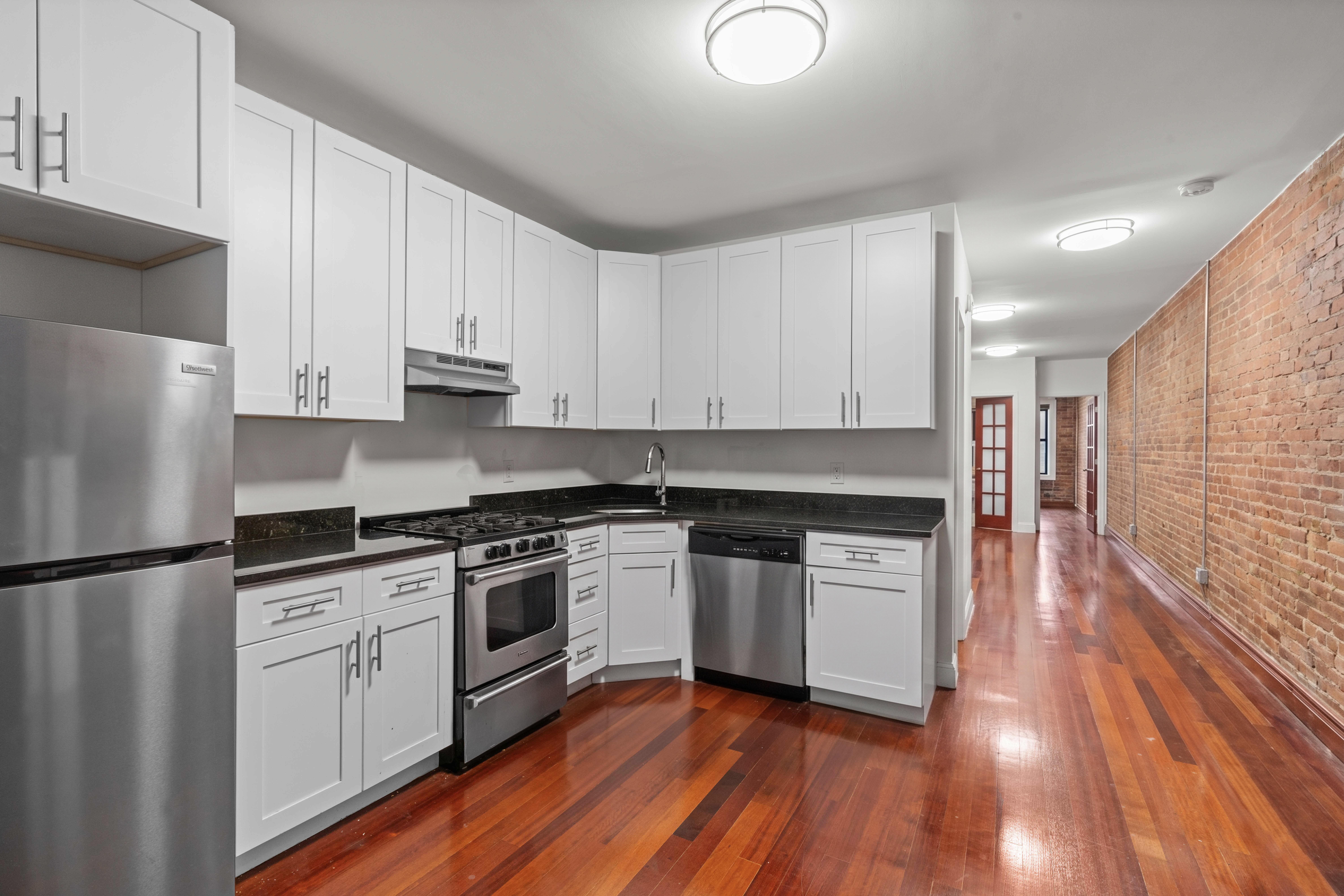 316 West 19th Street, Unit 2E Manhattan, NY 10011 - Photo 3 of 6 a kitchen with granite countertop white cabinets and white appliances