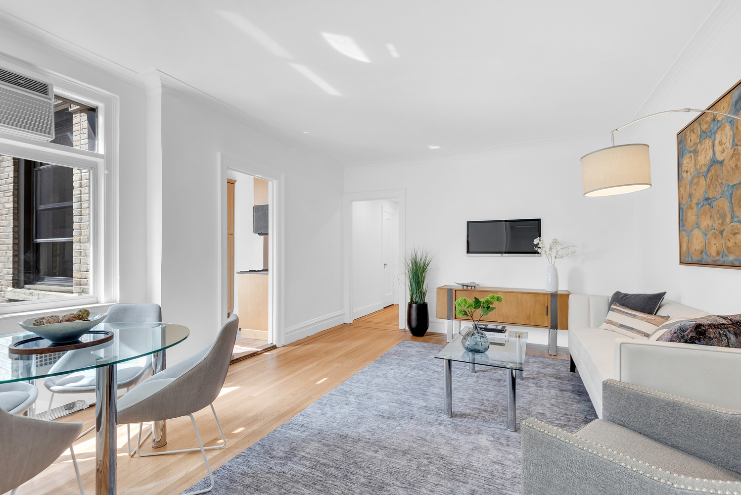 136 East 36th Street, Unit 11F Manhattan, NY 10016 - Photo 2 of 10 a living room with furniture and a flat screen tv with kitchen view
