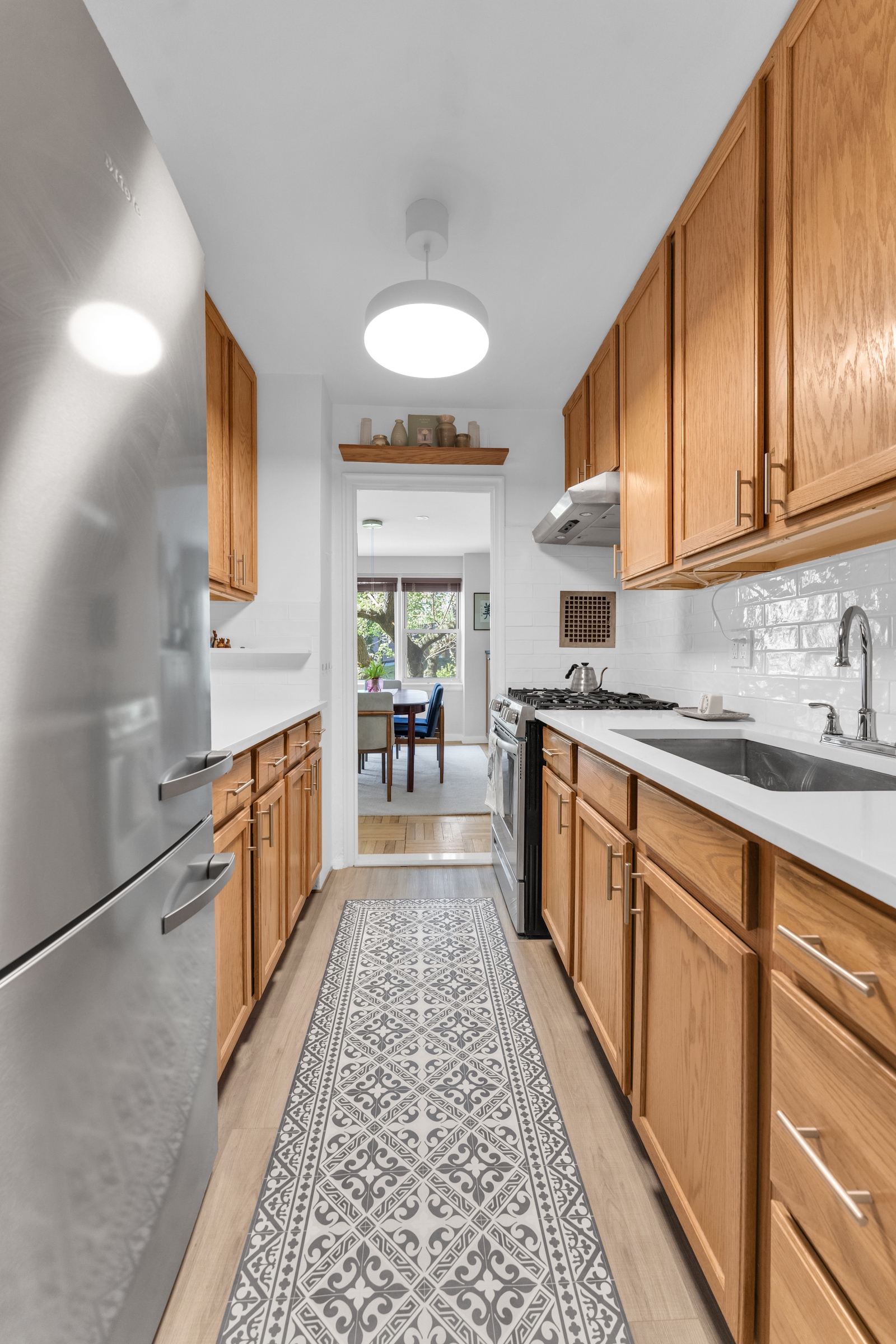 4555 Henry Hudson Parkway West, Unit A310 Bronx, NY 10471 - Photo 7 of 16 a large kitchen with stainless steel appliances granite countertop a refrigerator a sink dishwasher a stove and white countertops with wooden floor