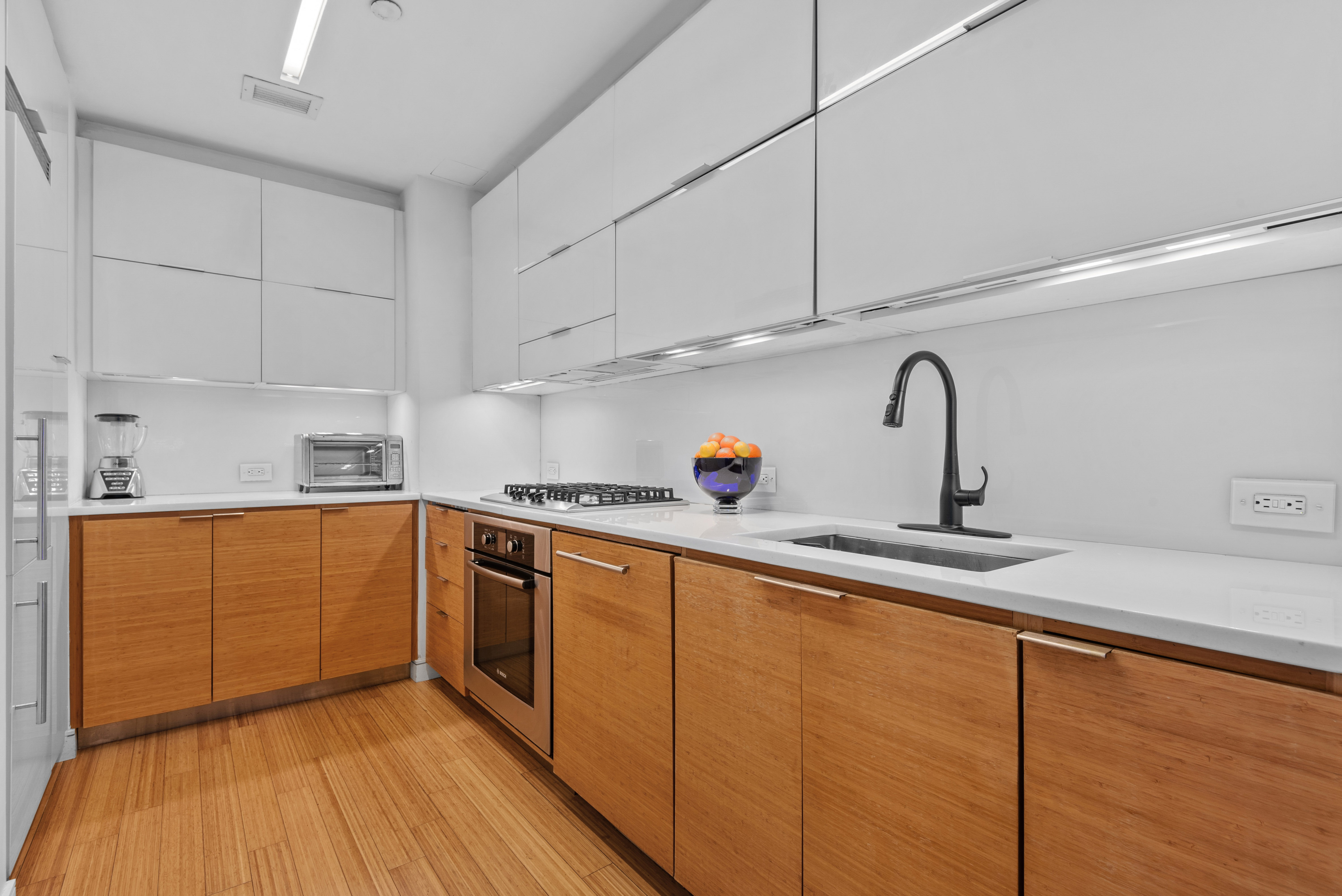303 East 33rd Street, Unit B2 Manhattan, NY 10016 - Photo 4 of 24 a kitchen with stainless steel appliances granite countertop a sink and wooden cabinets