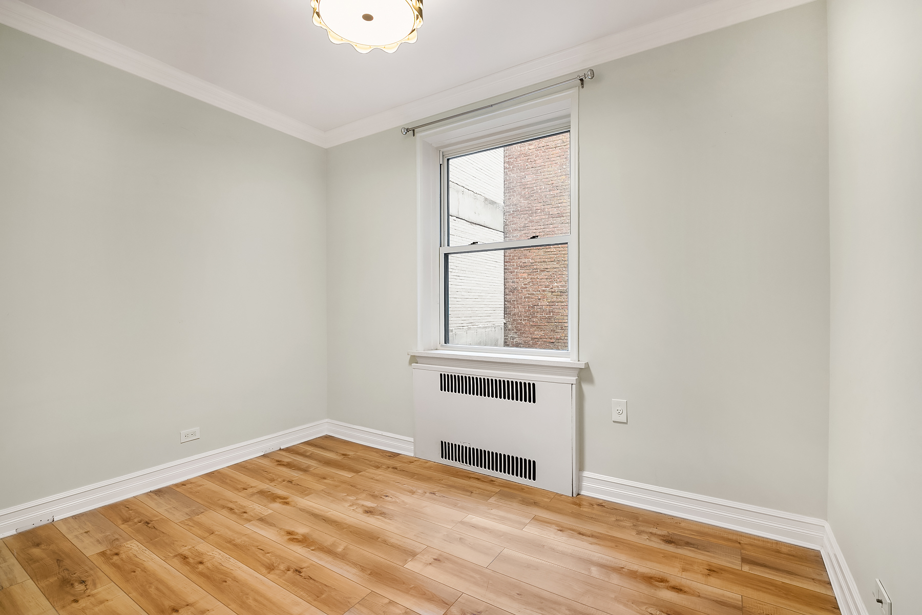 305 West 52nd Street, Unit 2J Manhattan, NY 10019 - Photo 10 of 13 a view of an empty room with wooden floor and a window
