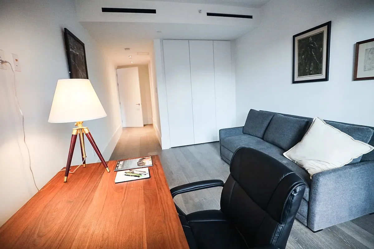 a living room with a bed and a lamp on table with wooden floor