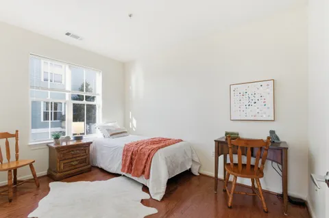 a bedroom with a bed and a bookshelf with wooden floor