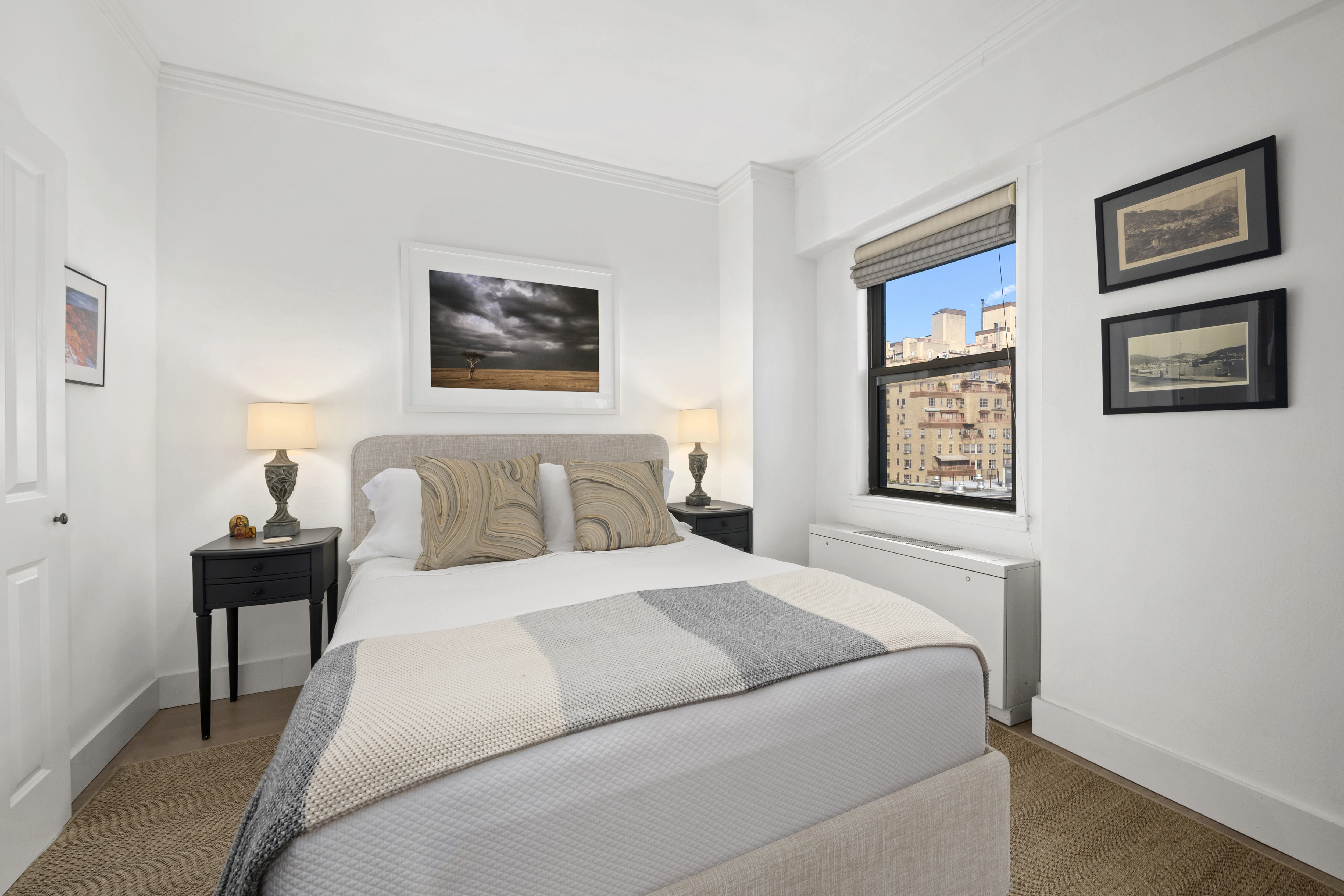 201 East 21st Street, Unit 12M Manhattan, NY 10010 - Photo 5 of 10 a bedroom with a bed and a lamp on dresser with wooden floor